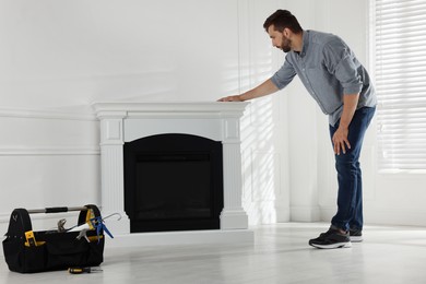 Man installing electric fireplace near white wall in room