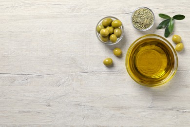 Photo of Glass bowl with fresh olive oil on white wooden table, flat lay. Space for text