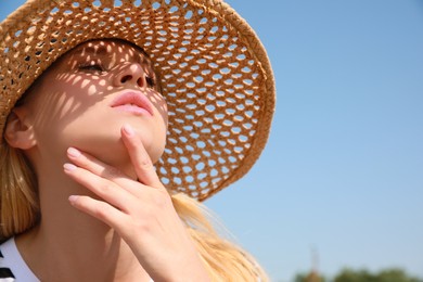 Photo of Beautiful woman with straw hat against blue sky on sunny day, space for text