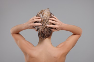 Photo of Woman washing hair on light grey background, back view