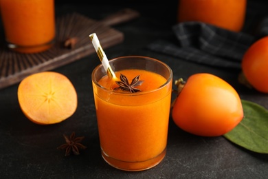 Photo of Tasty persimmon smoothie with anise and fresh fruits on black table