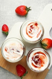 Photo of Tasty yoghurt with jam and strawberries on grey table, top view
