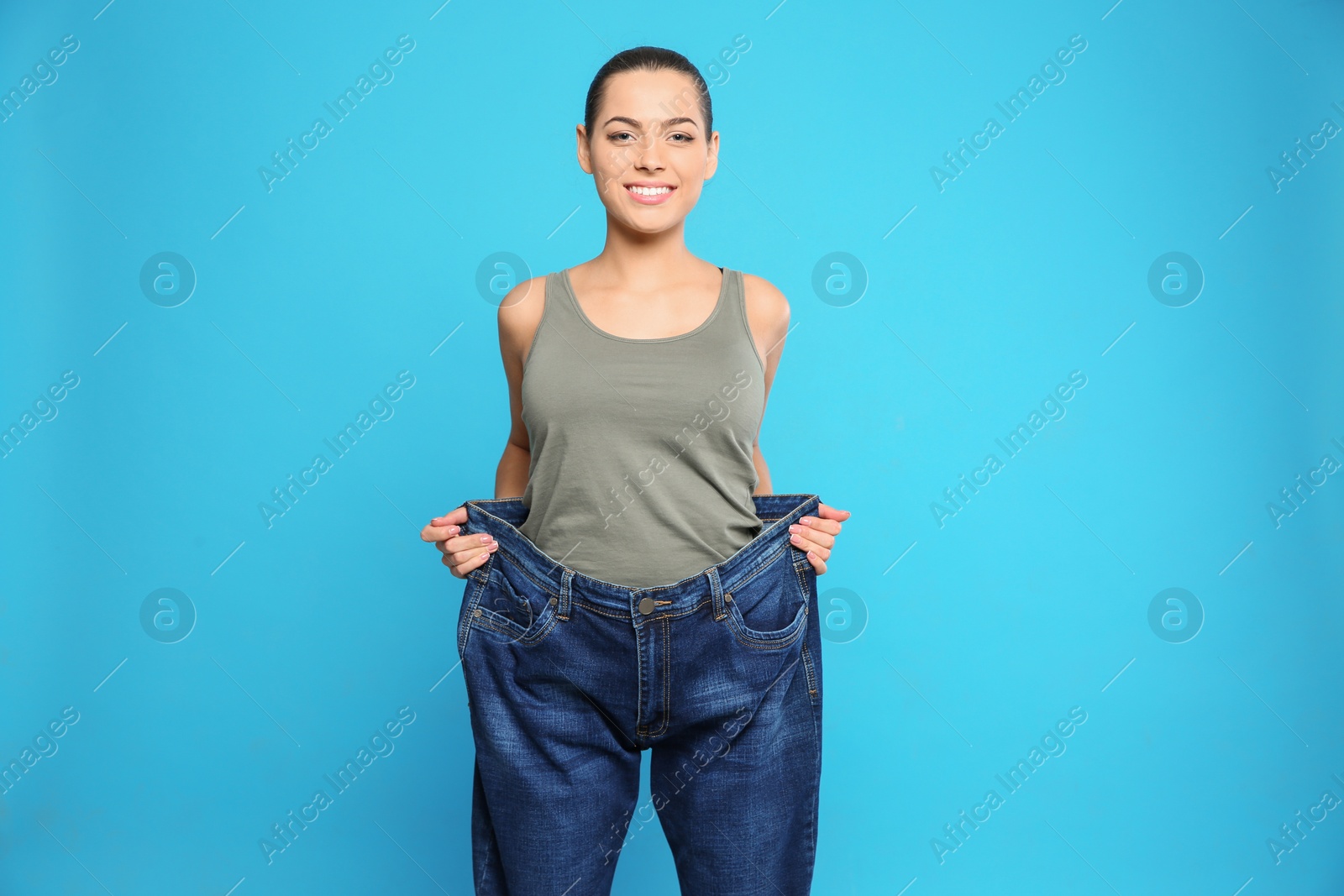 Photo of Slim woman in oversized jeans on color background. Weight loss