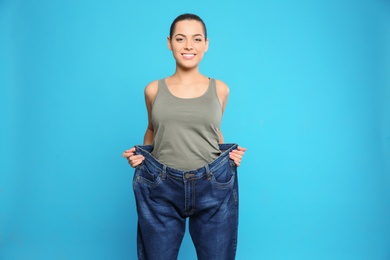 Photo of Slim woman in oversized jeans on color background. Weight loss