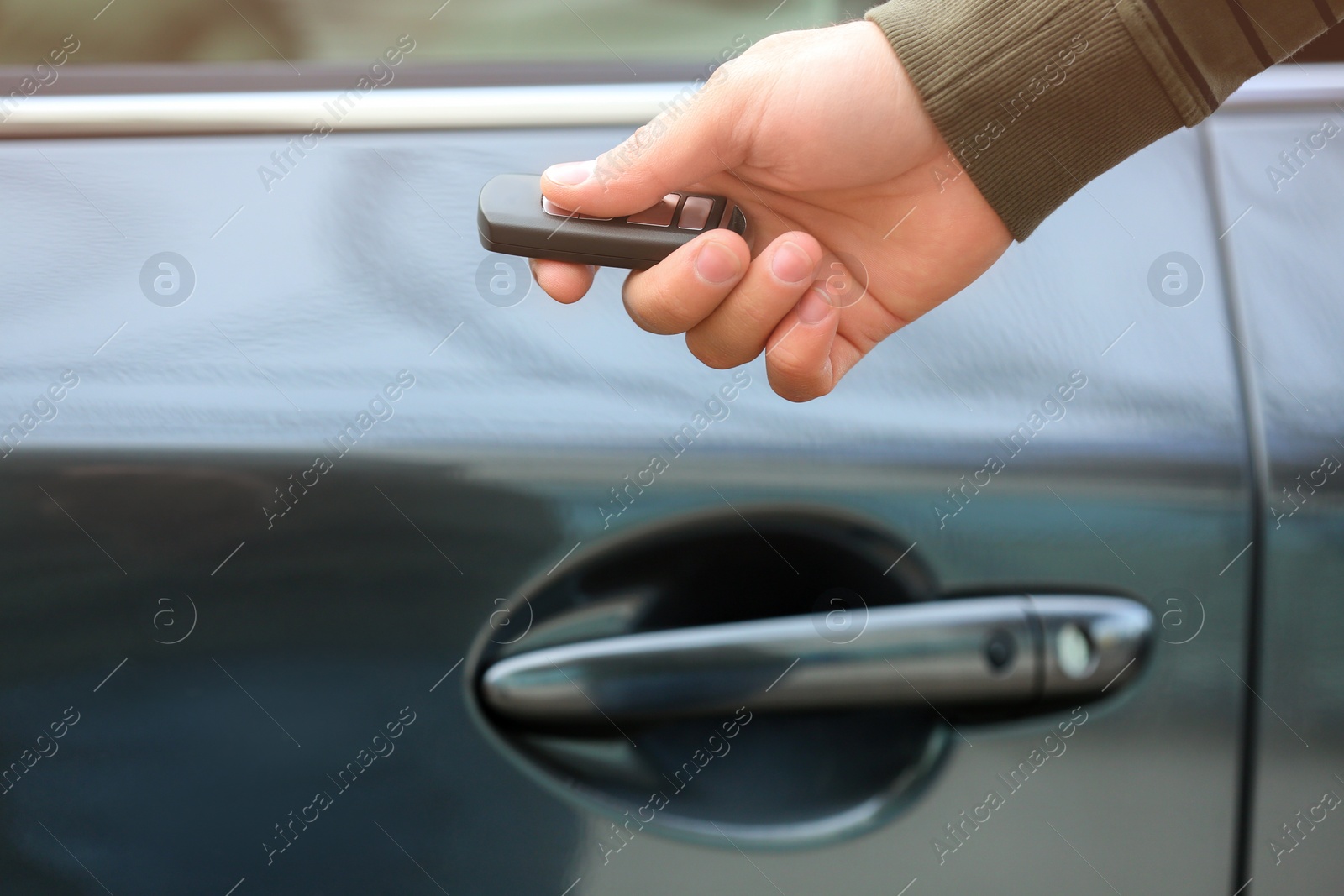 Photo of Closeup view of man opening car door with remote key