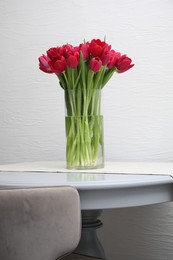 Bouquet of beautiful tulips in glass vase on table indoors