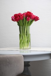 Photo of Bouquet of beautiful tulips in glass vase on table indoors