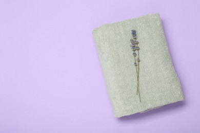 Photo of Soft towel and lavender flowers on violet background, top view. Space for text