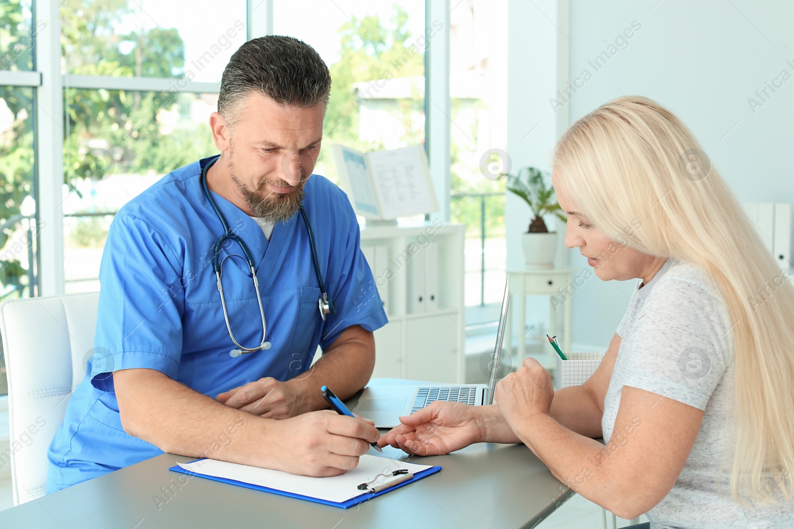 Photo of Male medical assistant consulting female patient in clinic