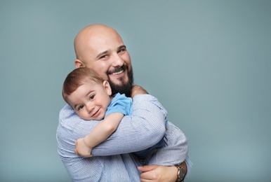 Portrait of dad and his little son on color background