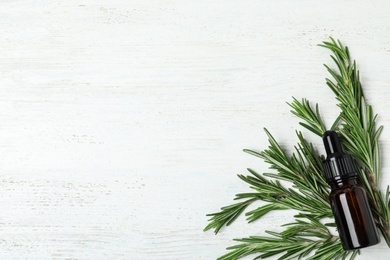 Photo of Flat lay composition with rosemary essential oil and space for text on white wooden background