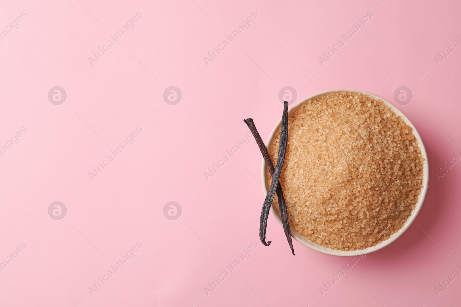 Photo of Bowl with brown vanilla sugar on color background, top view