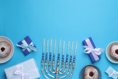 Photo of Flat lay composition with Hanukkah menorah and donuts on light blue background, space for text