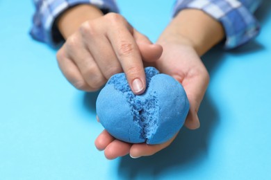 Photo of Woman playing with kinetic sand on light blue background, closeup