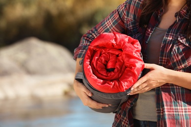 Female camper with sleeping bag outdoors, closeup. Space for text