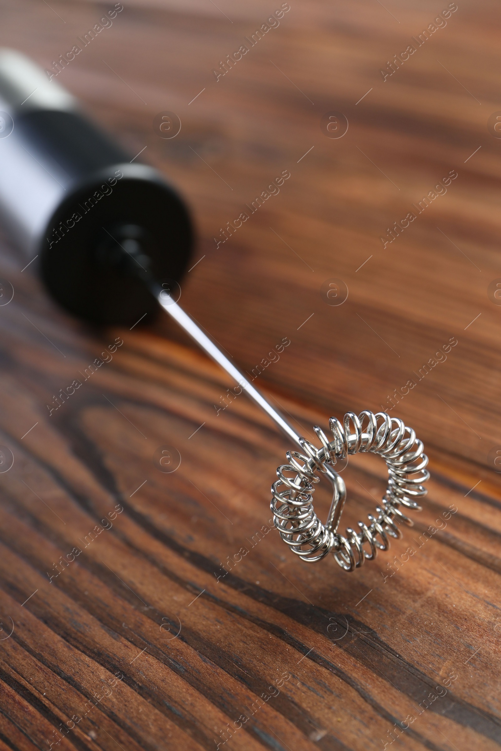 Photo of Black milk frother wand on wooden table, closeup