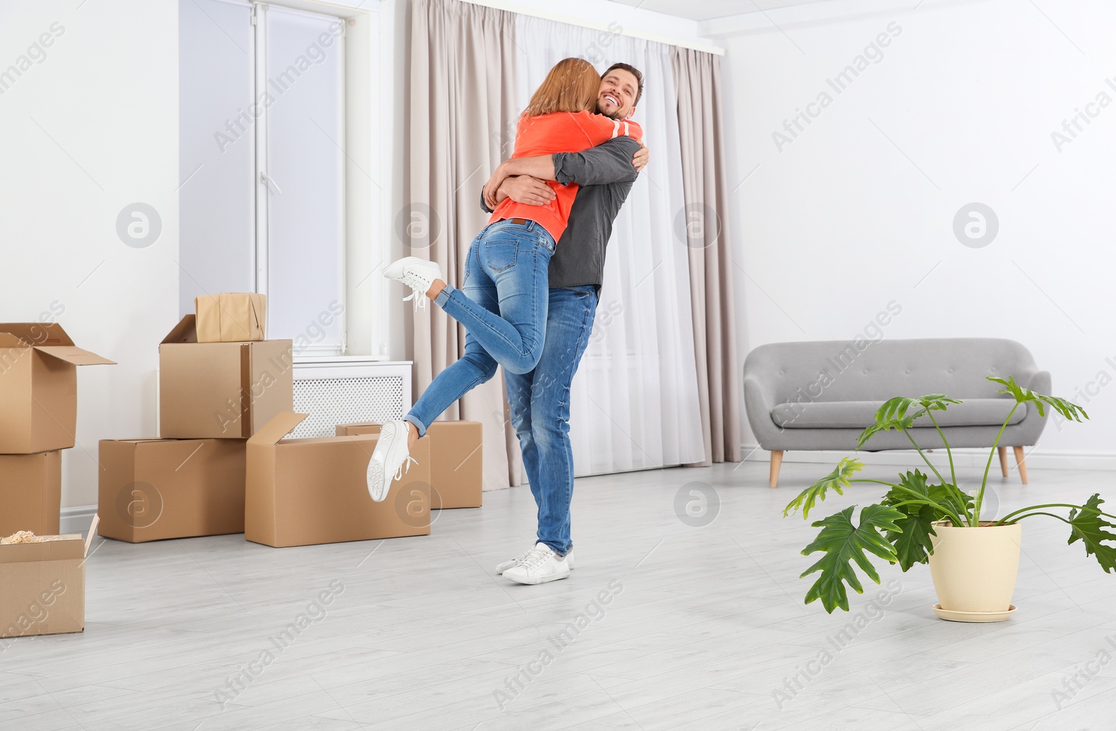 Photo of Happy couple hugging near moving boxes in their new house