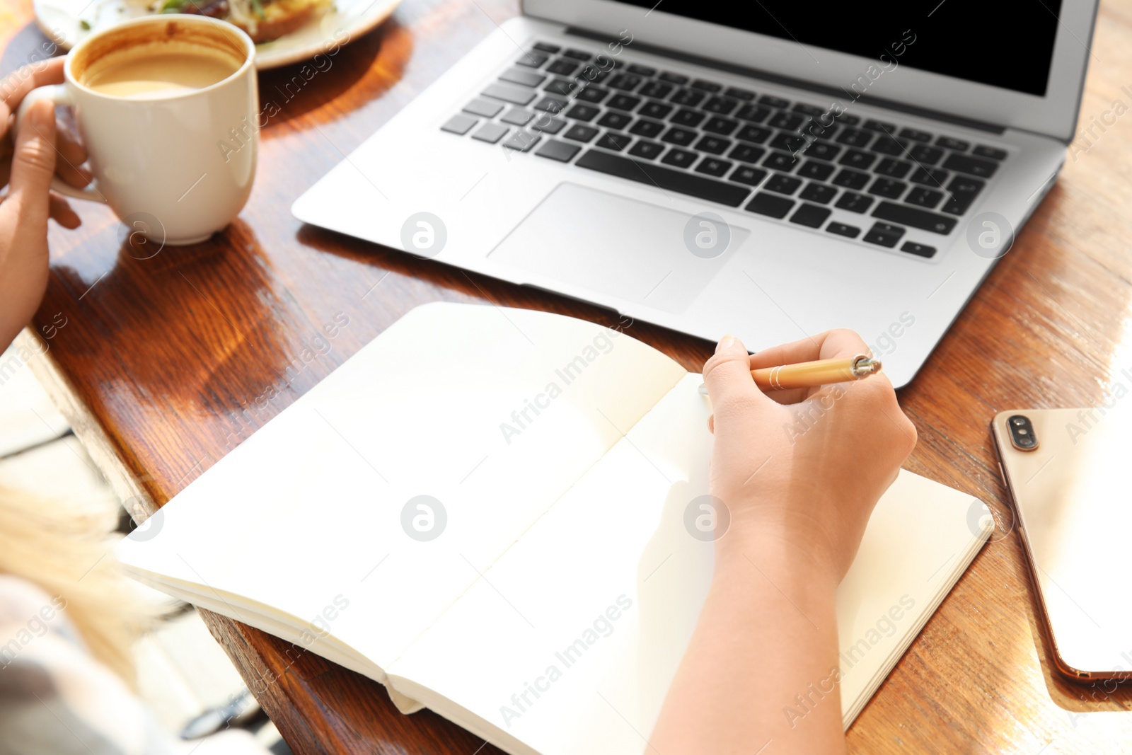 Photo of Woman writing blog content in notebook at table, closeup