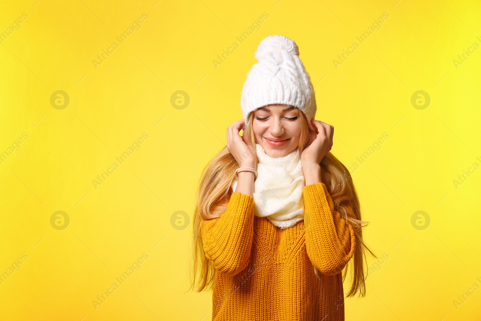 Photo of Portrait of emotional young woman in stylish hat, sweater and scarf on color background. Winter atmosphere