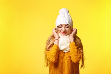 Portrait of emotional young woman in stylish hat, sweater and scarf on color background. Winter atmosphere