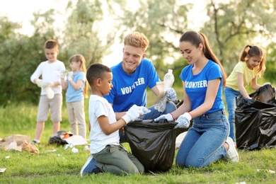 Photo of Little African-American boy collecting trash with volunteers in park