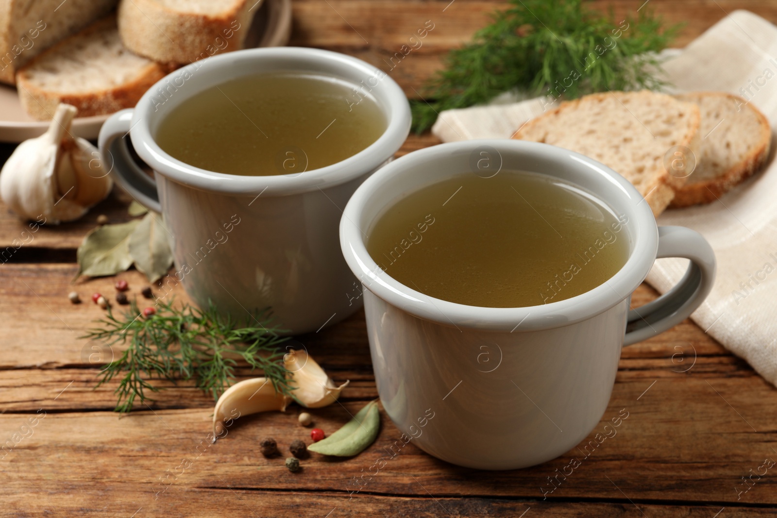 Photo of Hot delicious bouillon in cups on wooden table