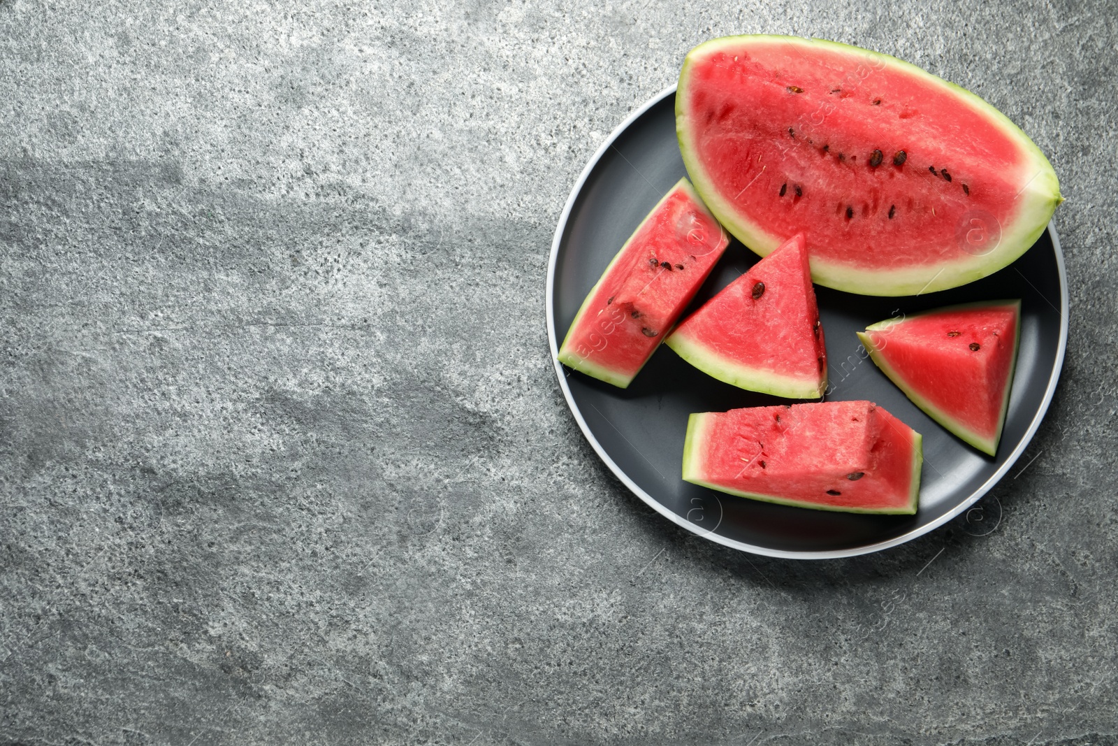 Photo of Delicious fresh watermelon slices on grey table, top view. Space for text