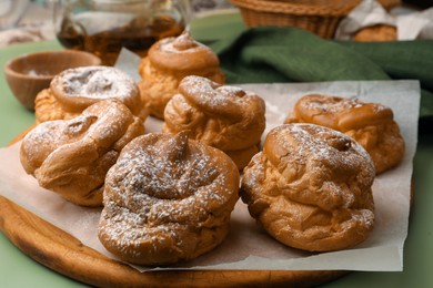 Photo of Delicious profiteroles with powdered sugar on green background