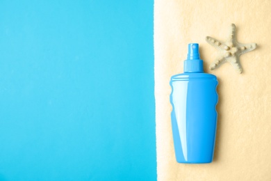 Bottle of sun protection body cream, starfish and towel on color background, top view with space for text