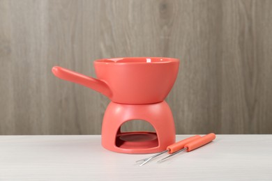 Photo of Fondue set on white wooden table. Kitchen equipment