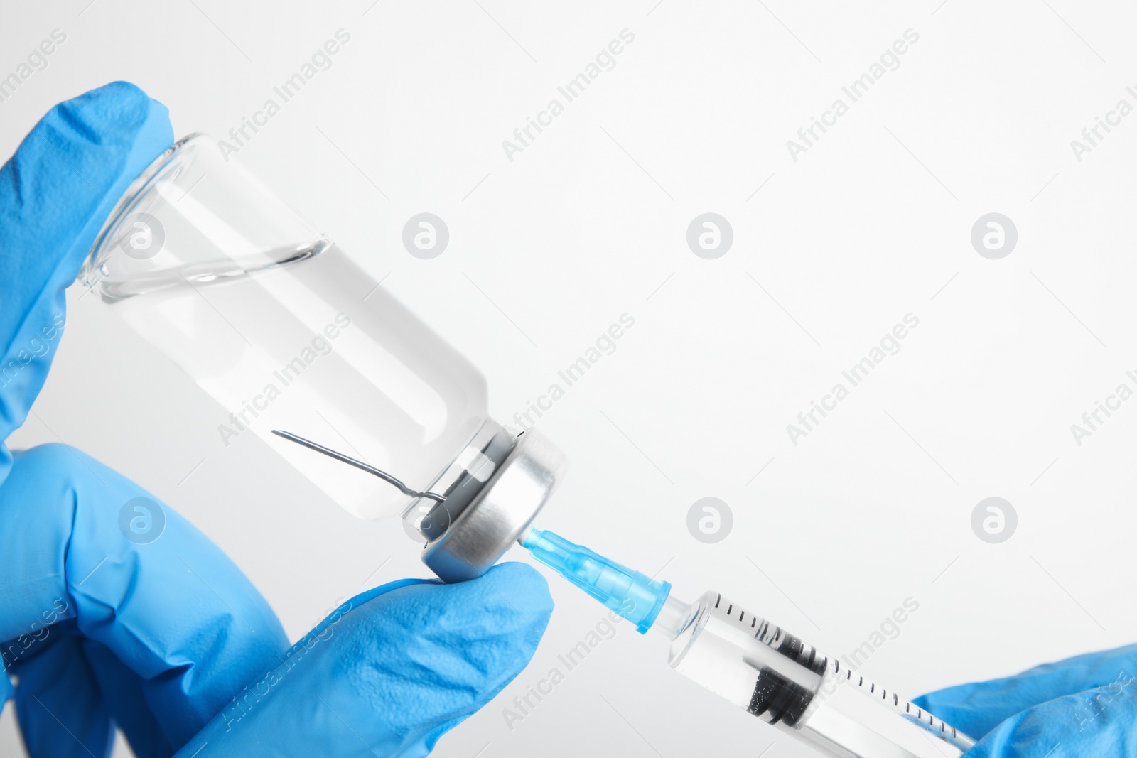 Photo of Doctor filling syringe with medication on white background, closeup. Vaccination and immunization