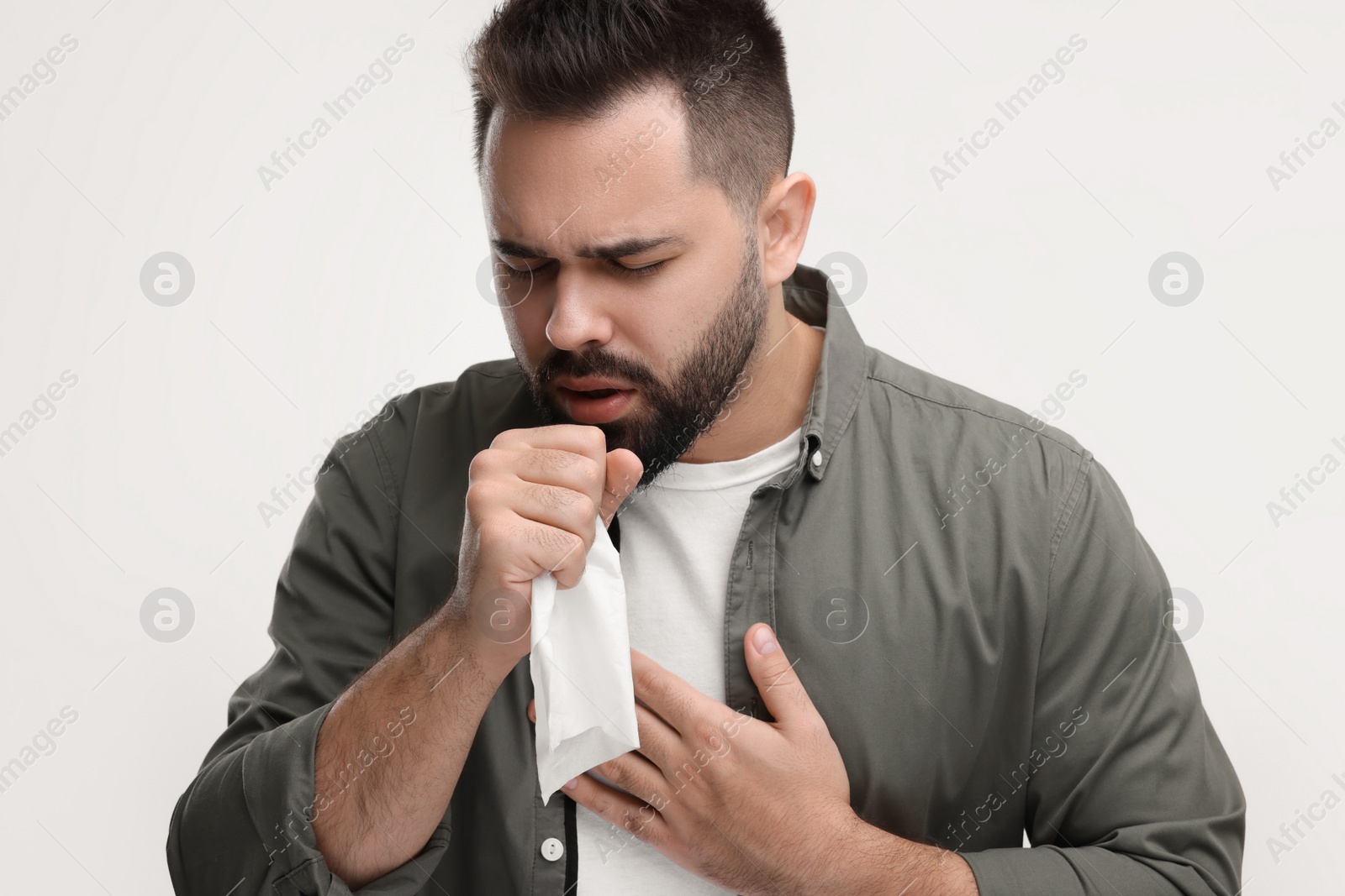 Photo of Sick man with tissue coughing on white background