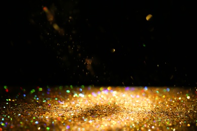 Photo of Many golden paillettes against black background. Space for text