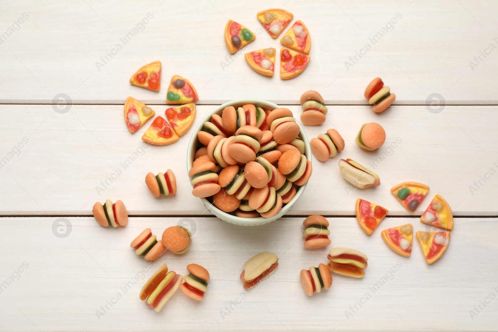 Photo of Many different delicious gummy candies on white wooden table, flat lay