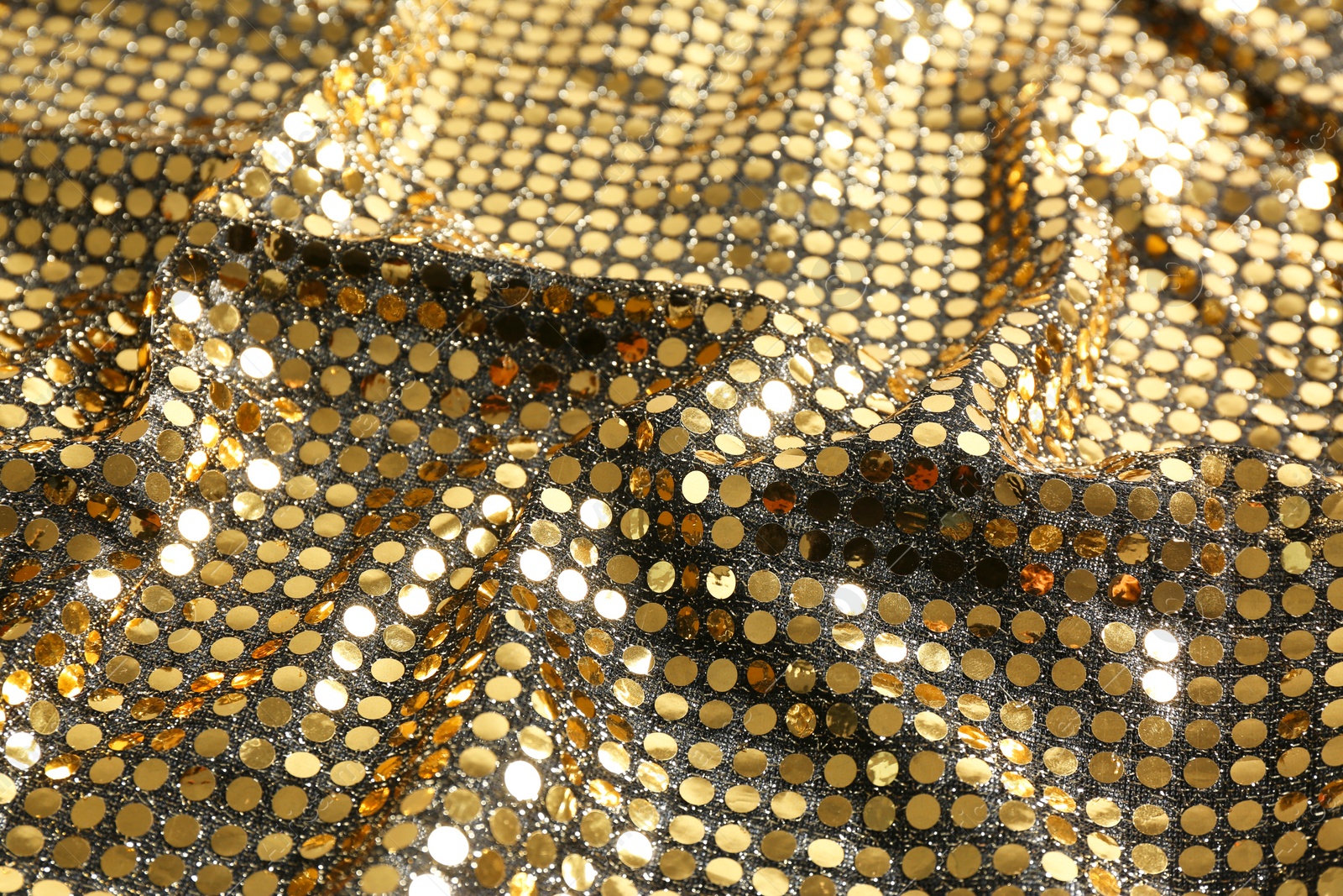 Photo of Closeup view of golden shiny sequin fabric as background