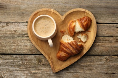 Photo of Delicious fresh croissant and cup of coffee on wooden table, top view