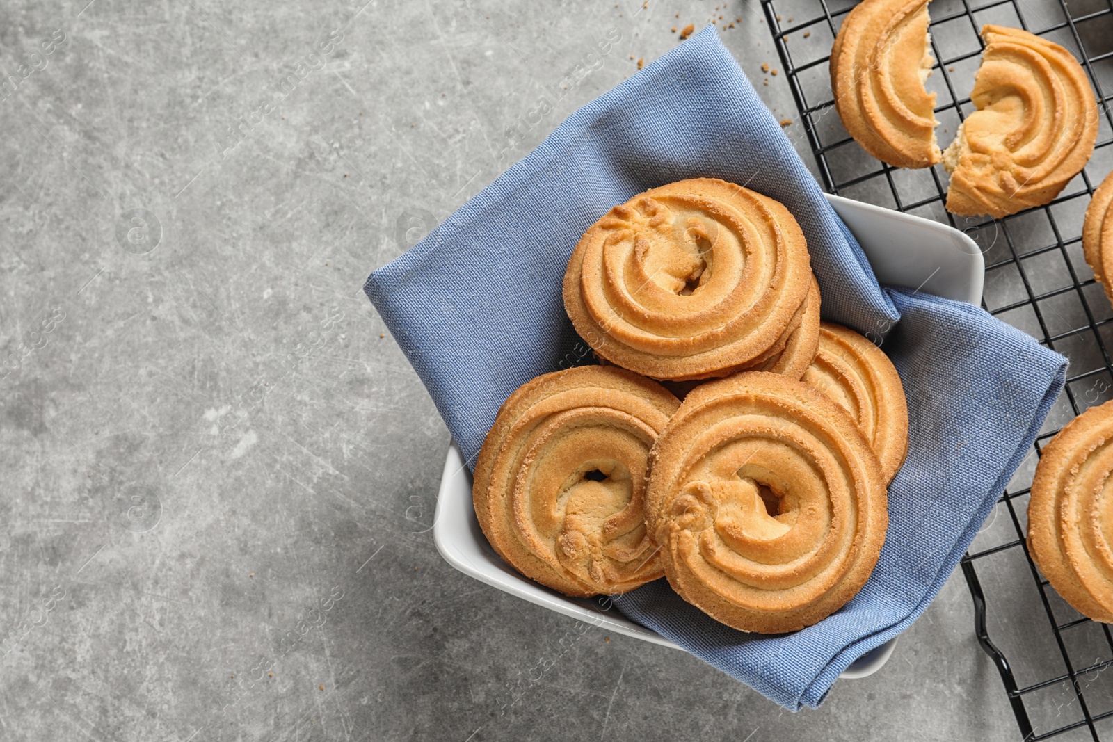 Photo of Bowl and baking rack with Danish butter cookies on grey table, top view. Space for text