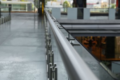 Photo of Glass barrier with metal handrail in modern building, closeup