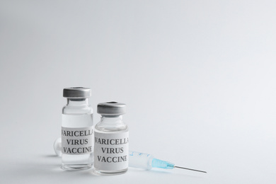 Photo of Chickenpox vaccine and syringe on light grey background, space for text. Varicella virus prevention