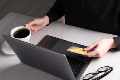 Photo of Online payment. Woman with laptop and credit card at white wooden table, closeup