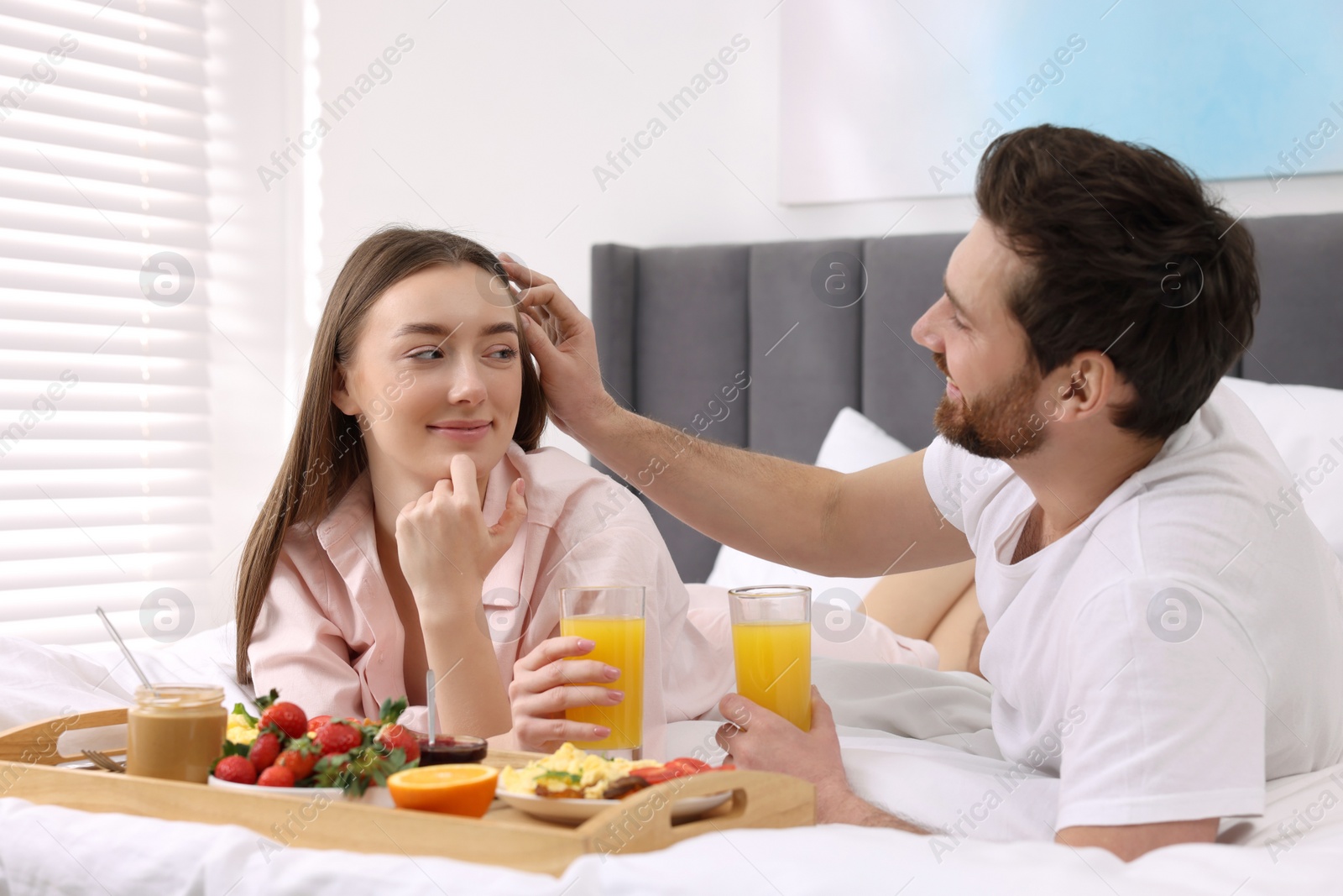 Photo of Happy couple eating tasty breakfast on bed at home