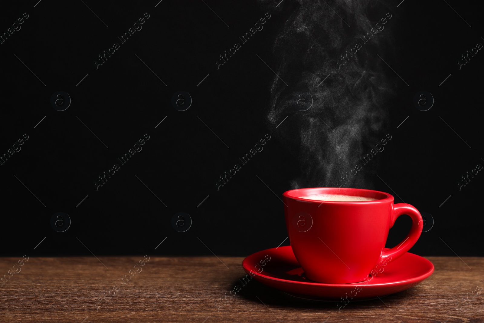 Image of Red cup with hot steaming coffee on wooden table against black background, space for text