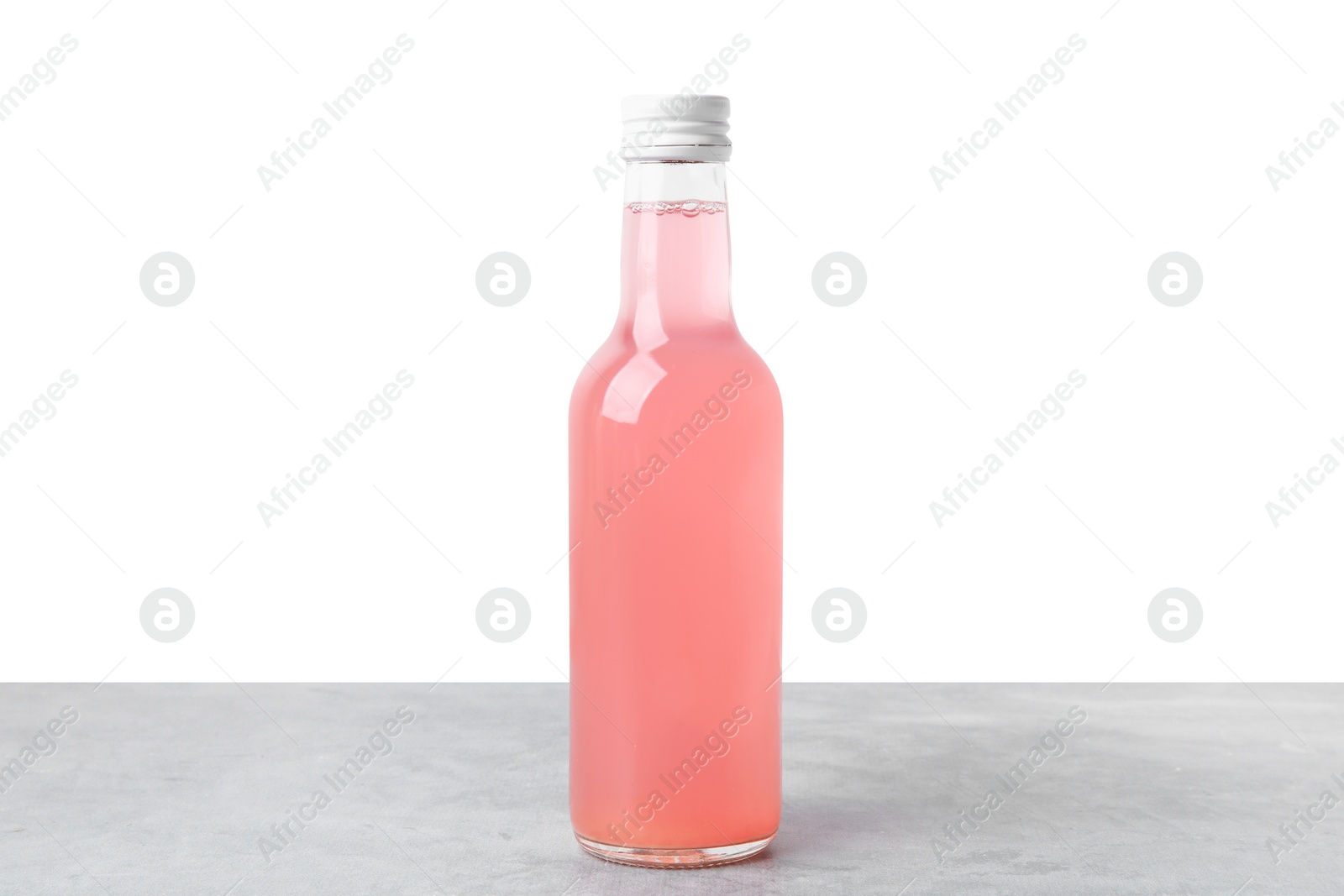 Photo of Delicious kombucha in glass bottle on grey table against white background