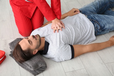 Woman in uniform practicing first aid on unconscious man indoors