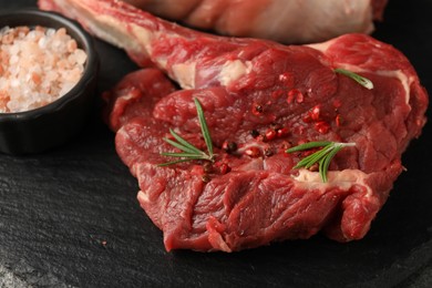 Photo of Raw ribeye steak and spices on grey table, closeup