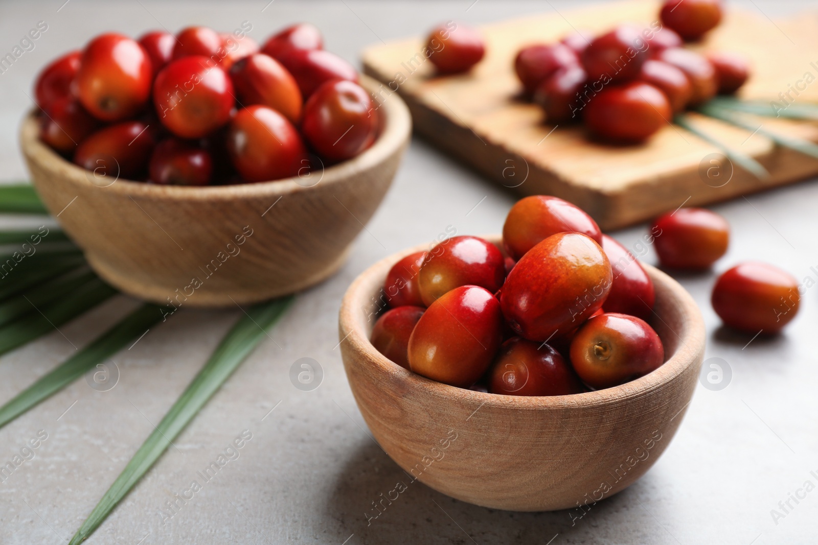 Photo of Palm oil fruits in bowl on grey table, closeup