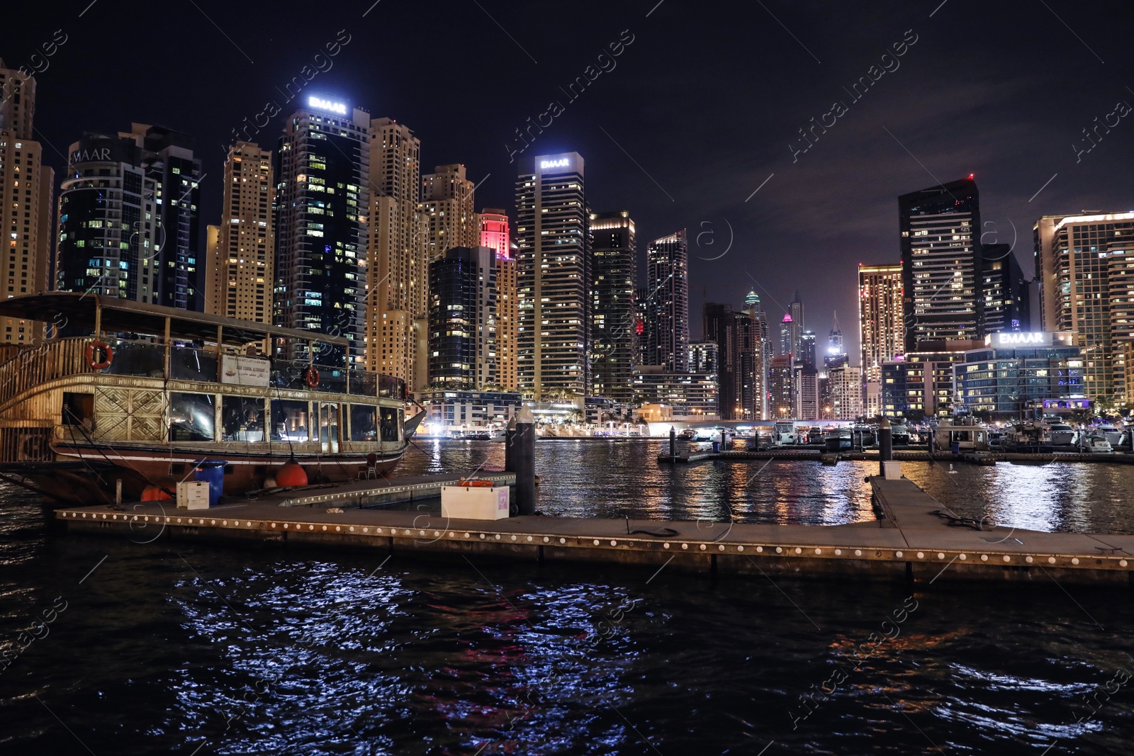 Photo of DUBAI, UNITED ARAB EMIRATES - NOVEMBER 03, 2018: Night cityscape of marina district with moored boat and illuminated buildings