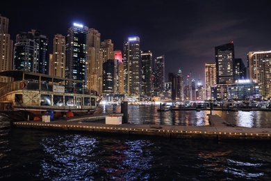 DUBAI, UNITED ARAB EMIRATES - NOVEMBER 03, 2018: Night cityscape of marina district with moored boat and illuminated buildings