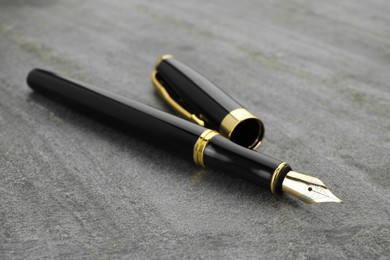 Photo of Stylish fountain pen on grey textured table, closeup