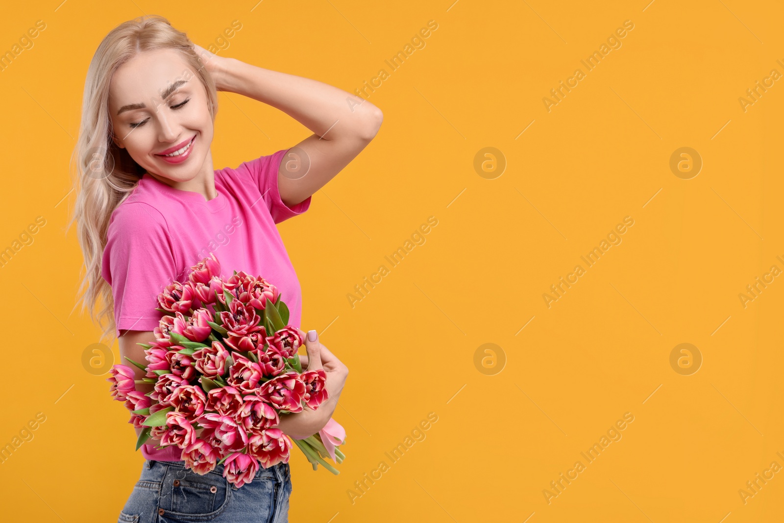 Photo of Happy young woman with beautiful bouquet on orange background. Space for text